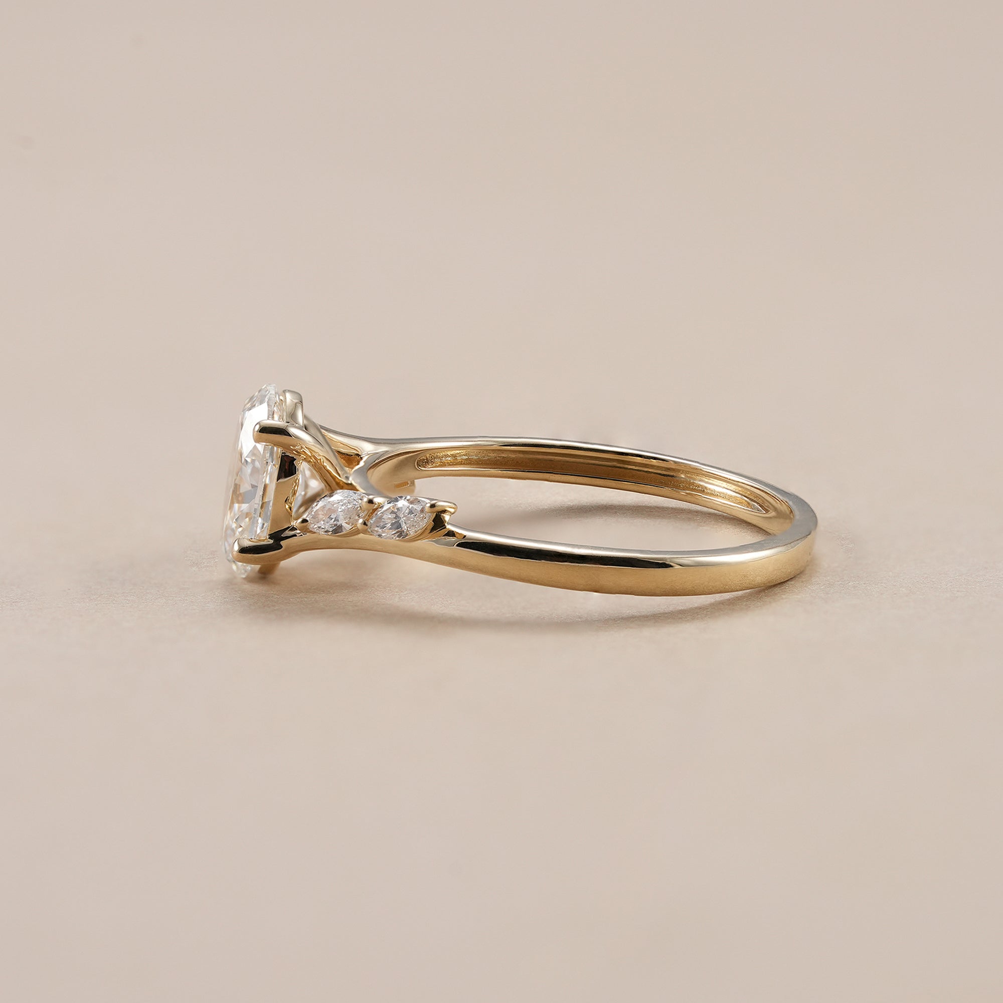 Yellow gold oval diamond engagement ring with marquise side stones.