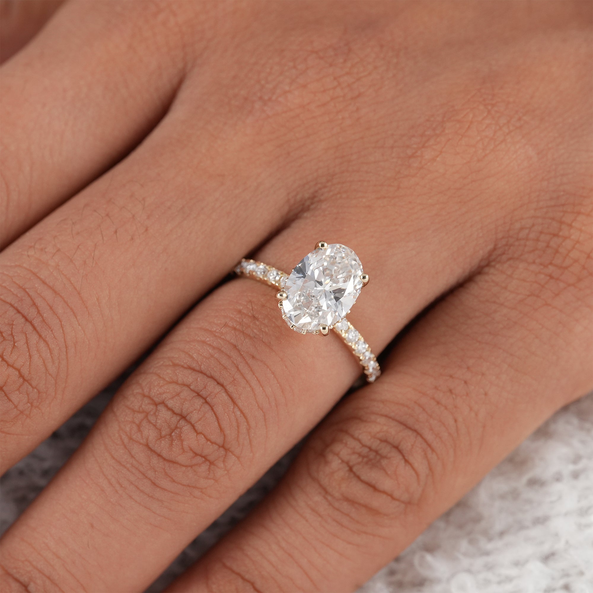 Hidden halo oval solitaire engagement ring with fine pavé accents.