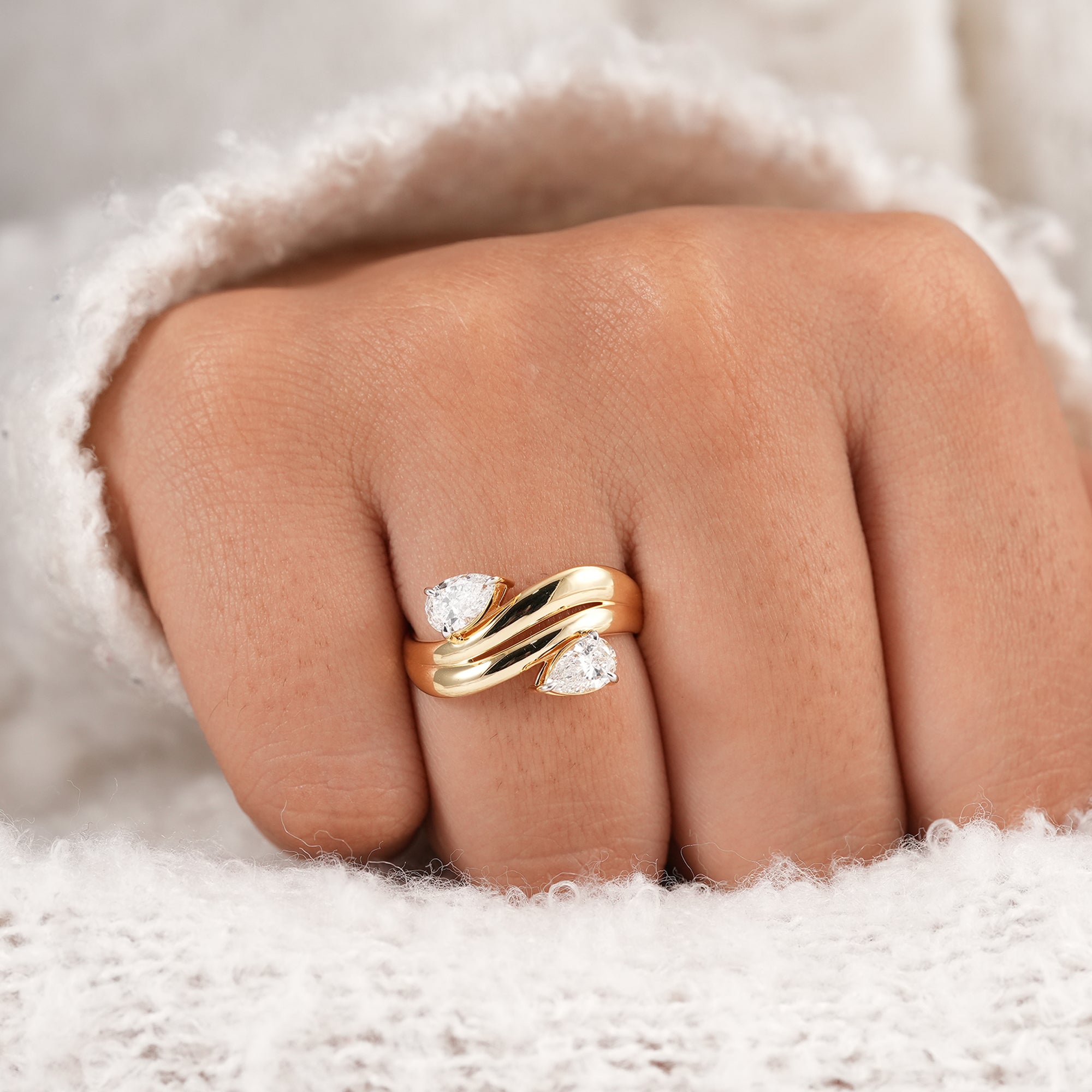 Two pear shaped lab diamonds set on a bold wave wedding band