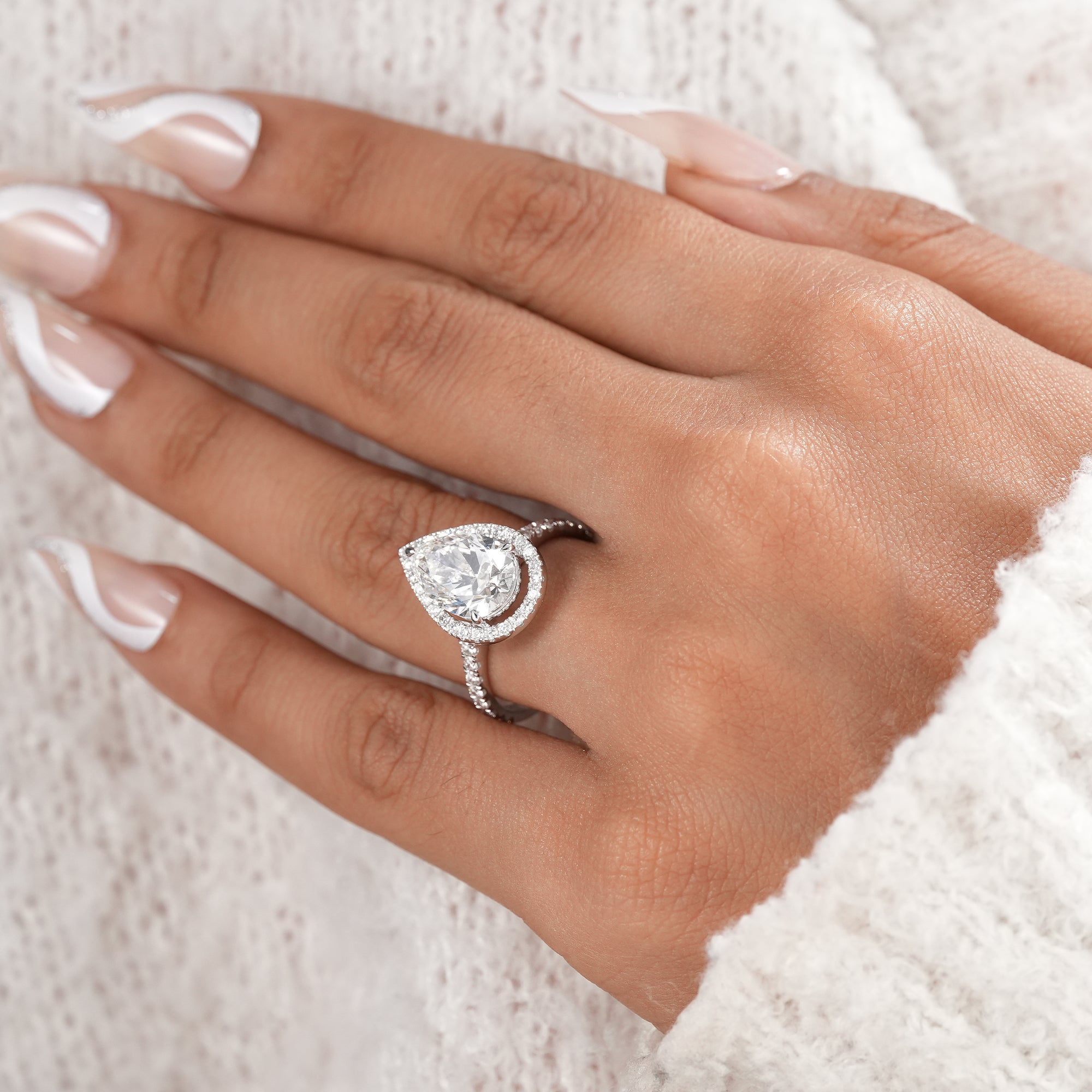 Elegant bridal ring featuring a pear cut diamond halo.