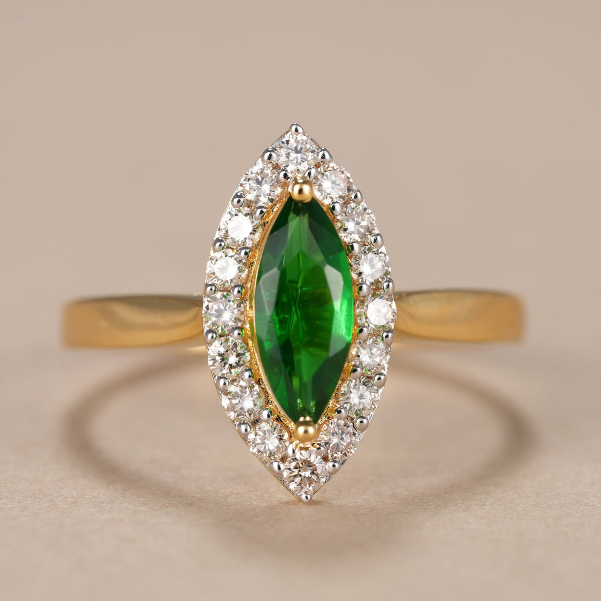Marquise emerald halo ring featuring sparkling lab grown diamonds in polished yellow gold.