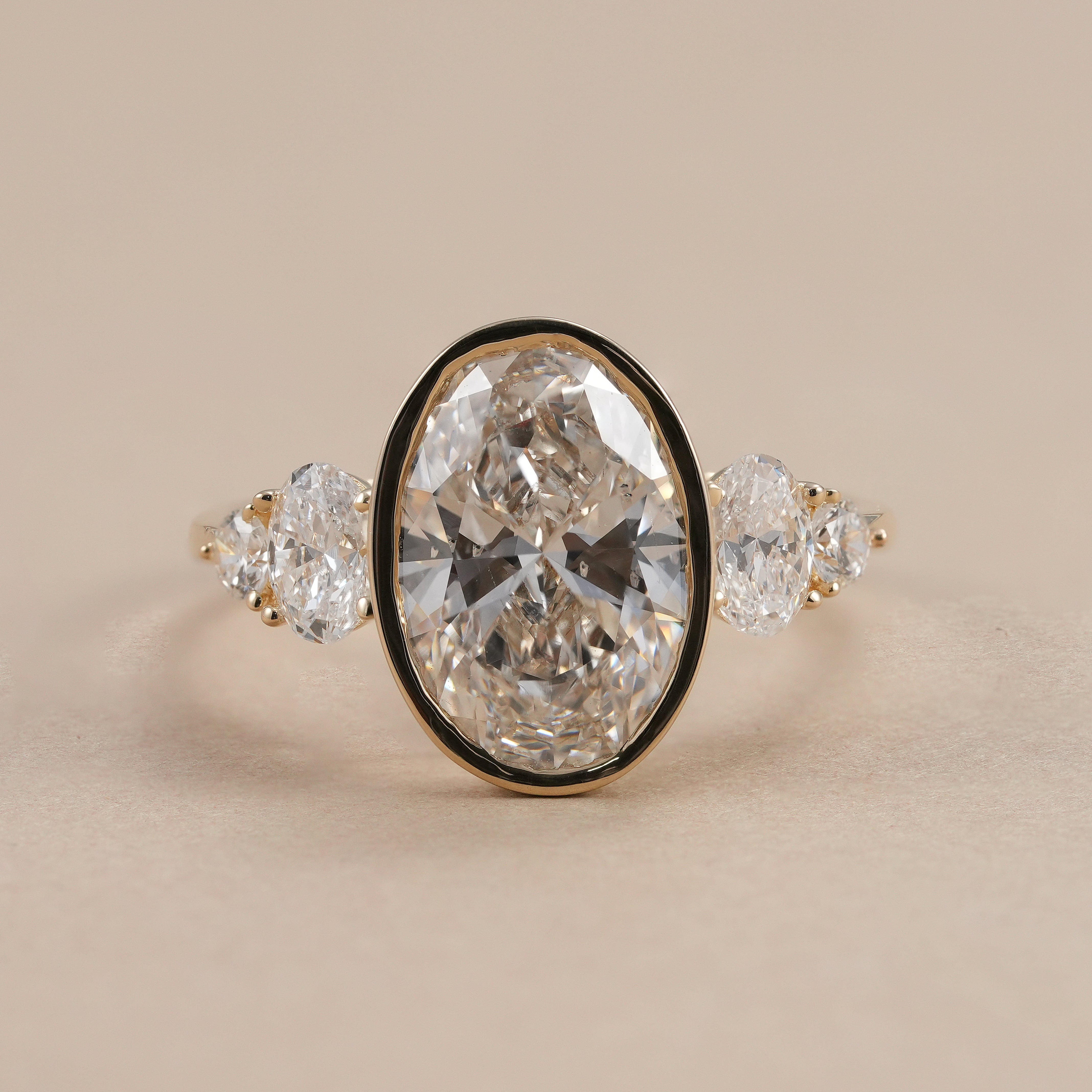 Oval bezel set lab grown diamond ring with oval and round side stones