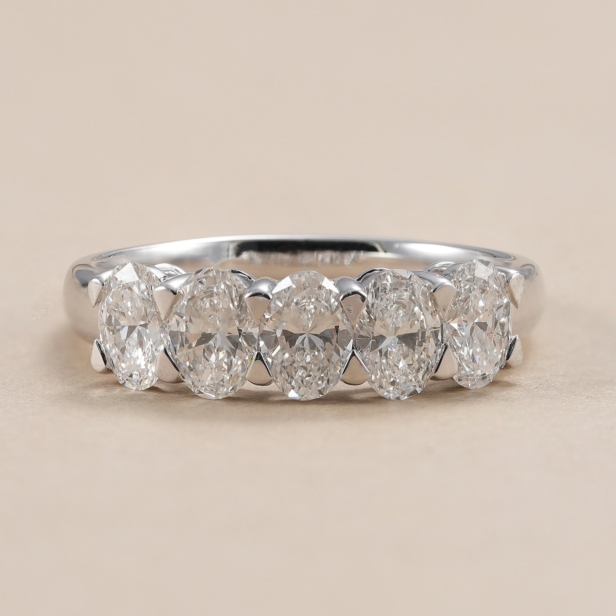Oval lab diamond five stone wedding band in polished white gold.