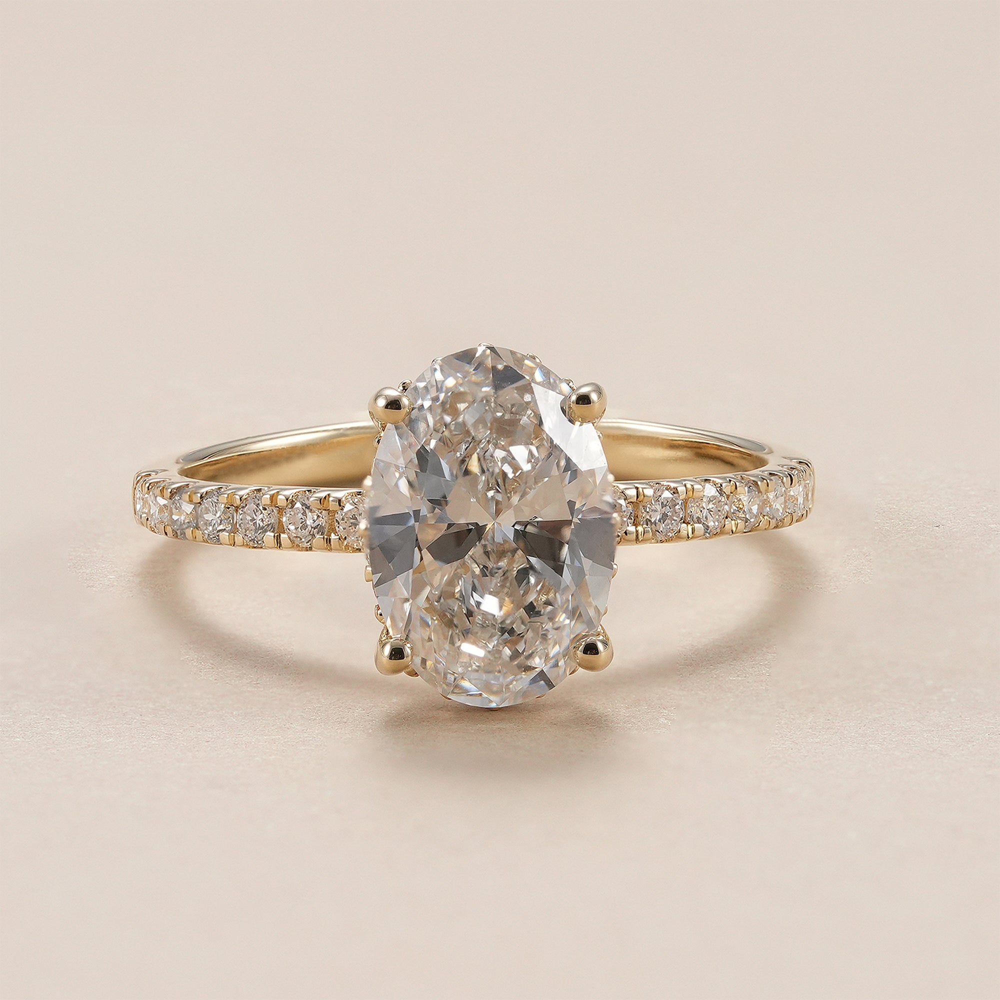Oval lab grown diamond hidden halo engagement ring with pavé band in yellow gold.