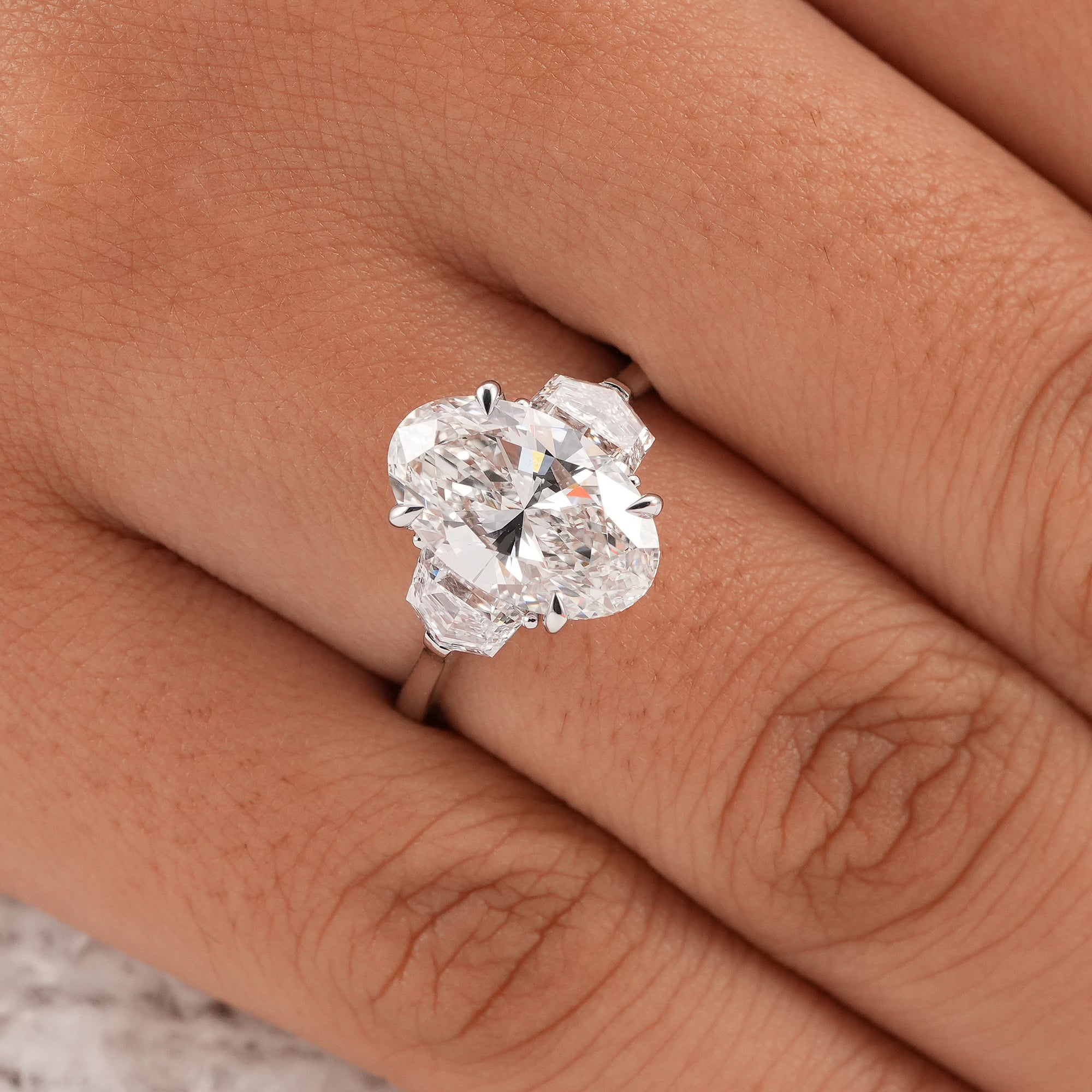 Elegant three stone oval diamond ring with tapered side stones