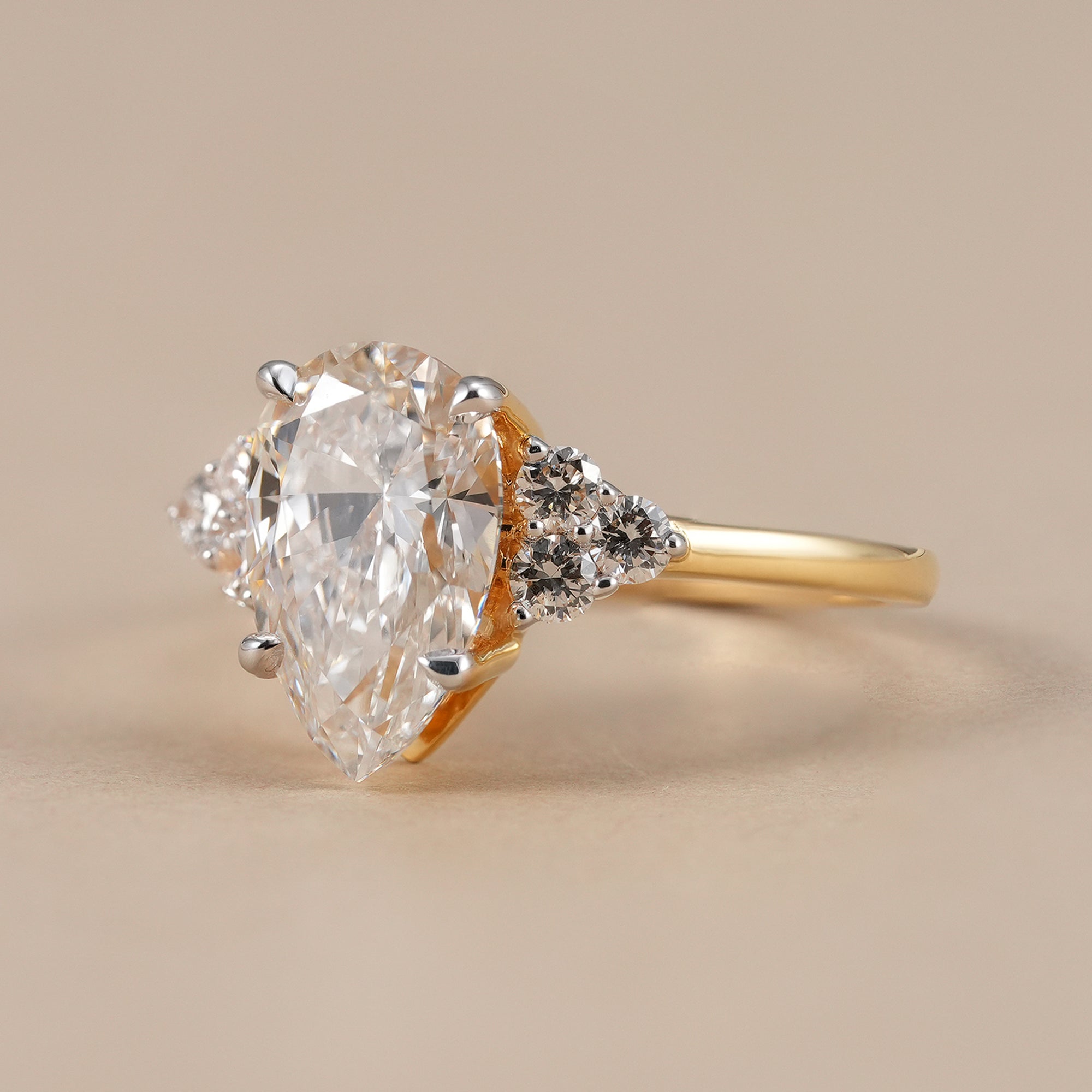 Pear cut diamond engagement ring with floral diamond side clusters