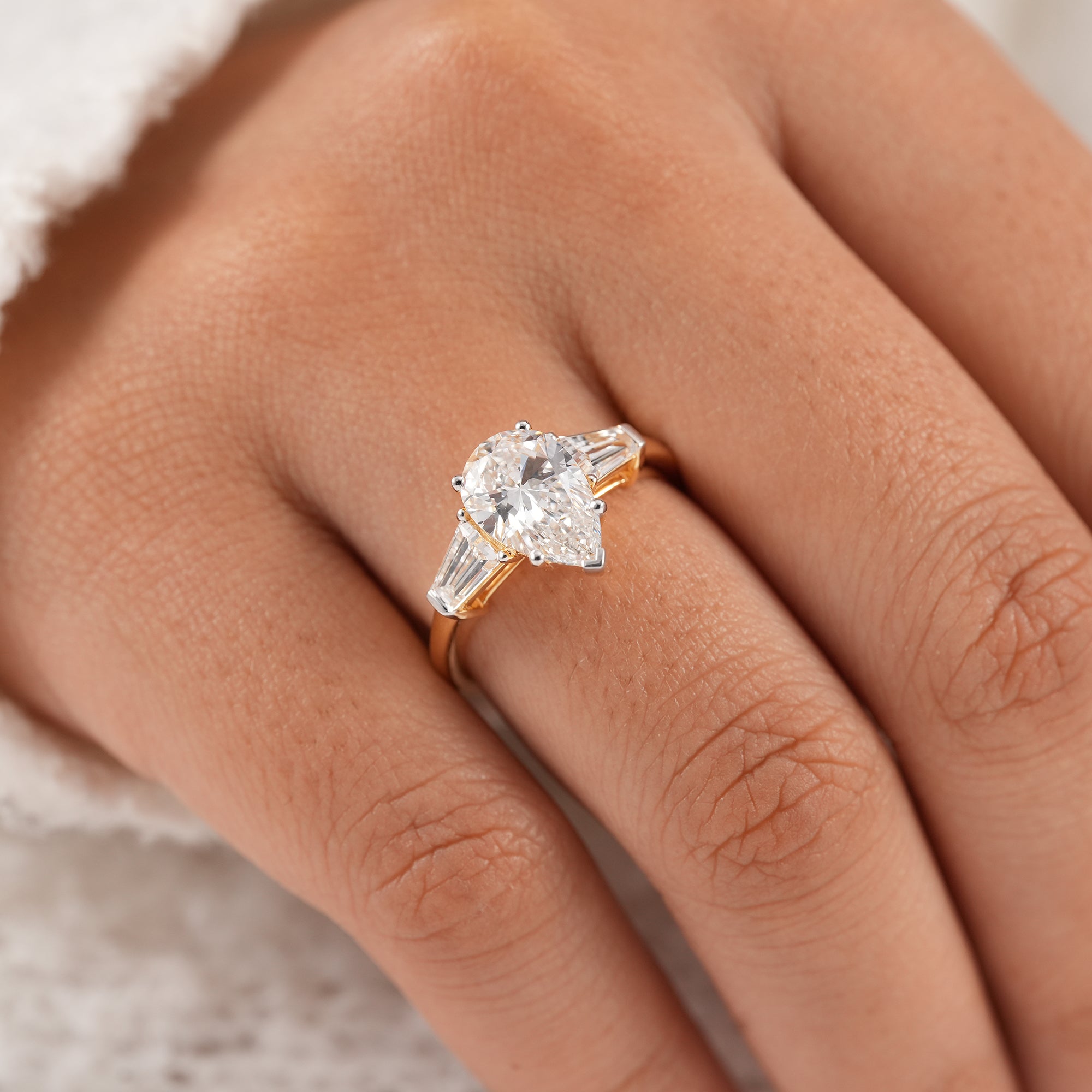 Pear diamond ring with tapered baguette side stones in yellow gold