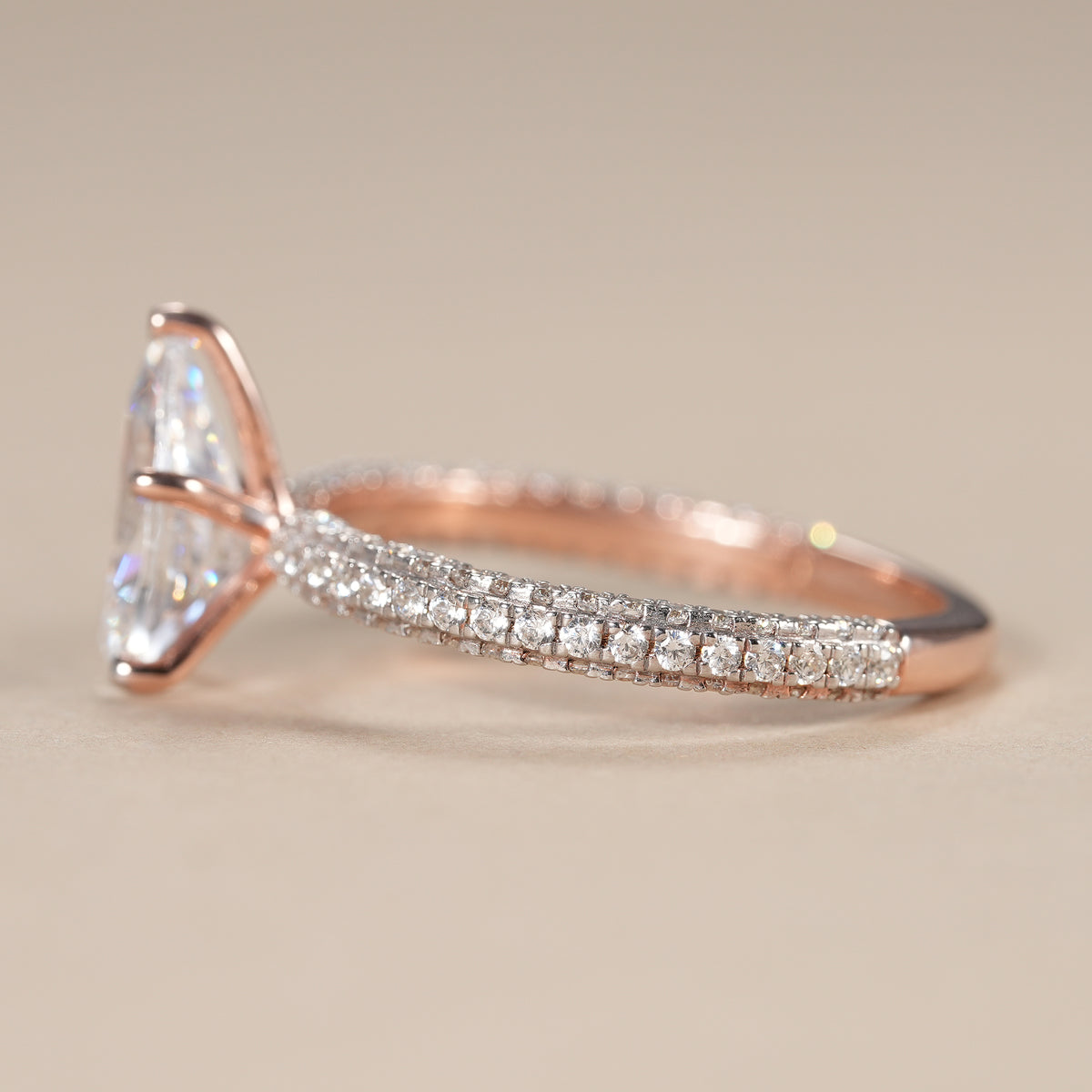 Elegant pear solitaire engagement ring with a shimmering micro pavé diamond band.