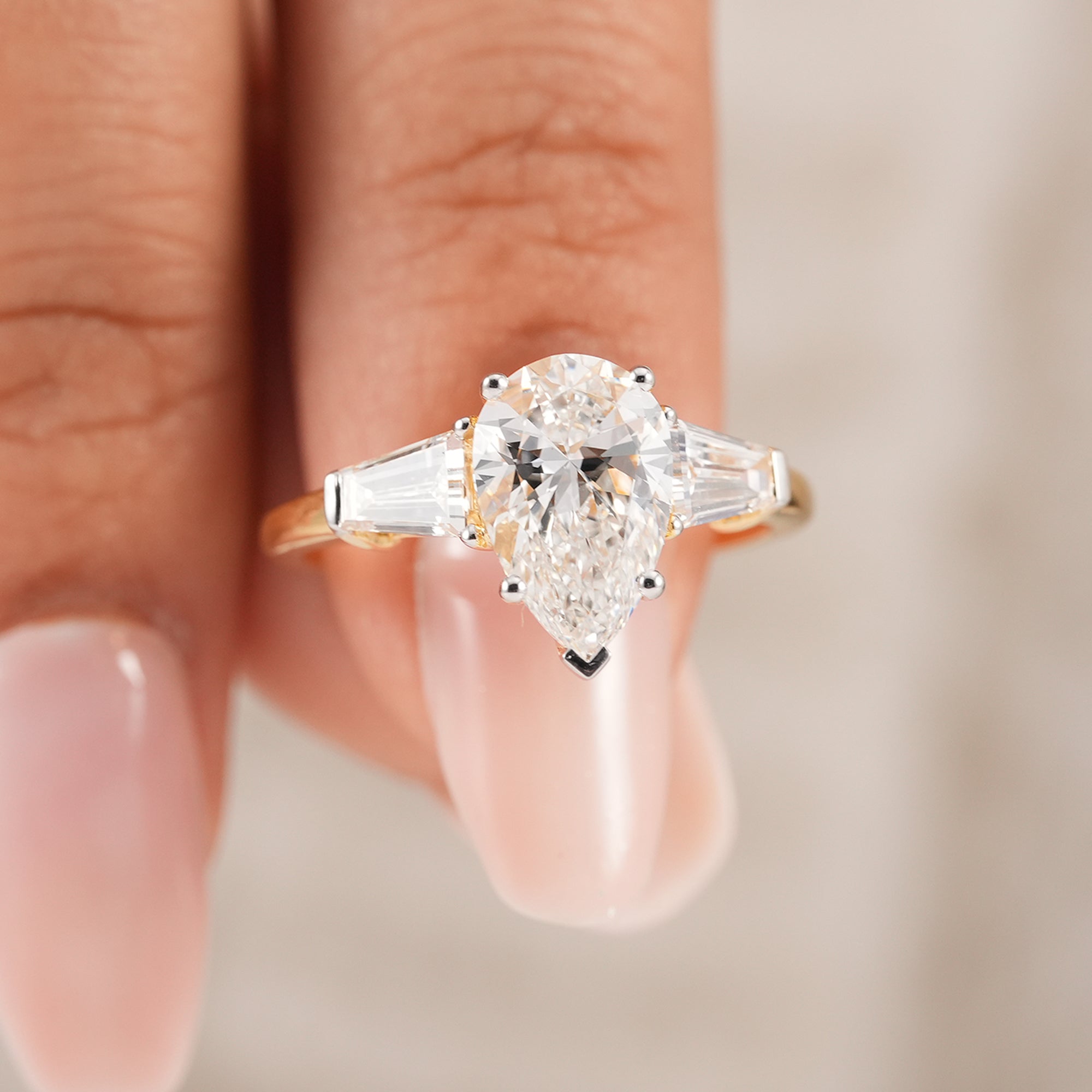 Pear three stone lab diamond ring featuring tapered baguette accents