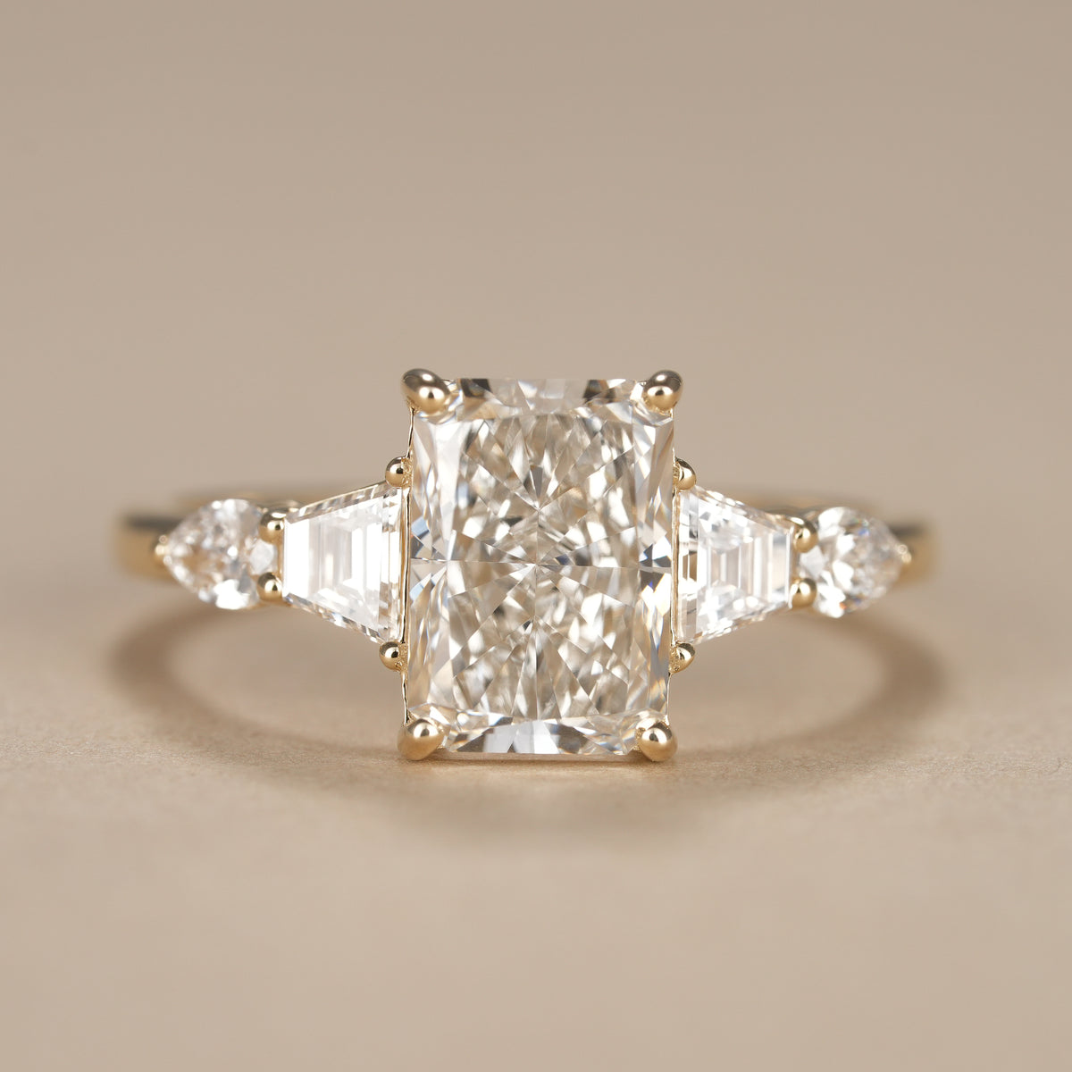 Radiant lab grown diamond engagement ring featuring tapered baguette and pear side stones in solid gold.