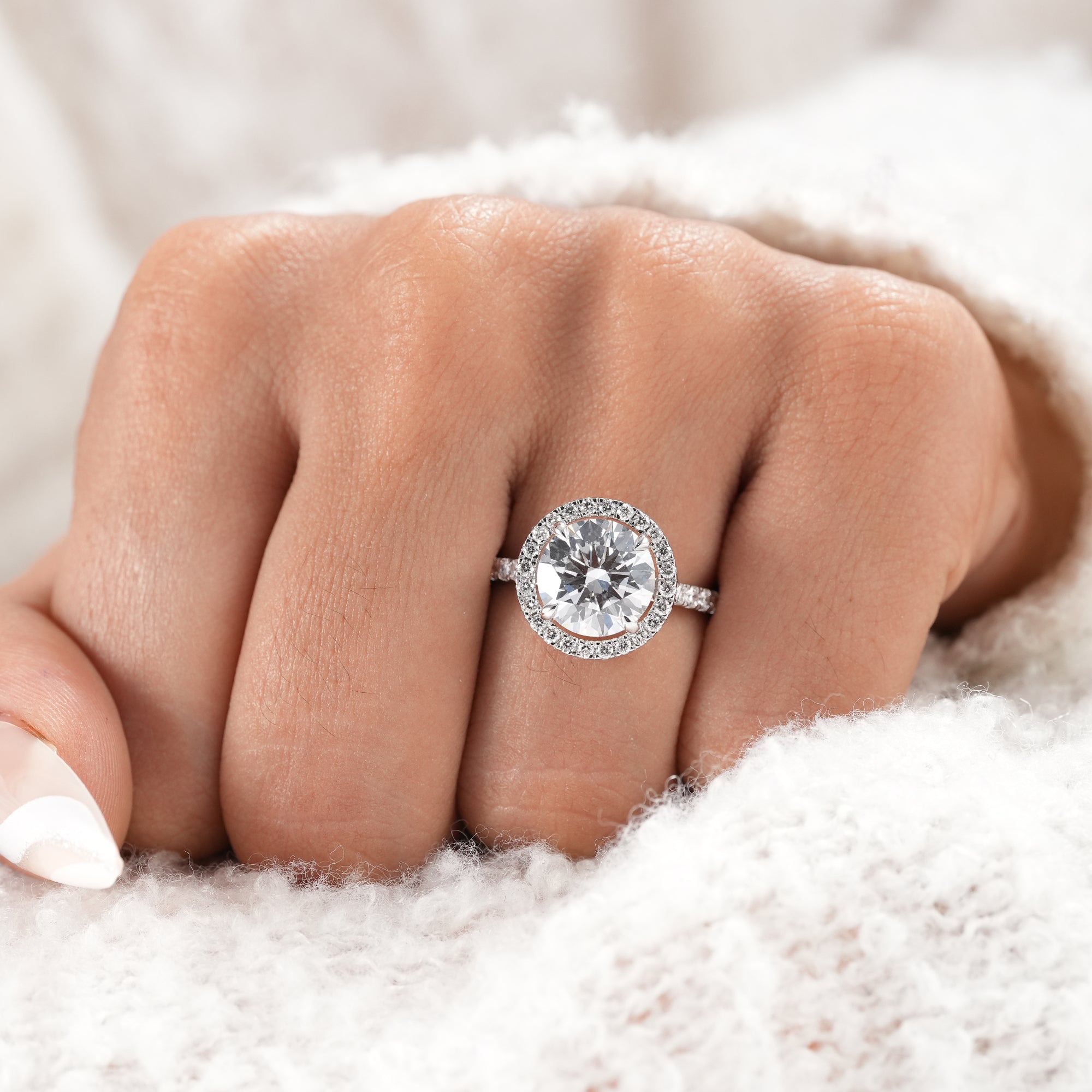 White gold round diamond halo ring with pavé diamonds.