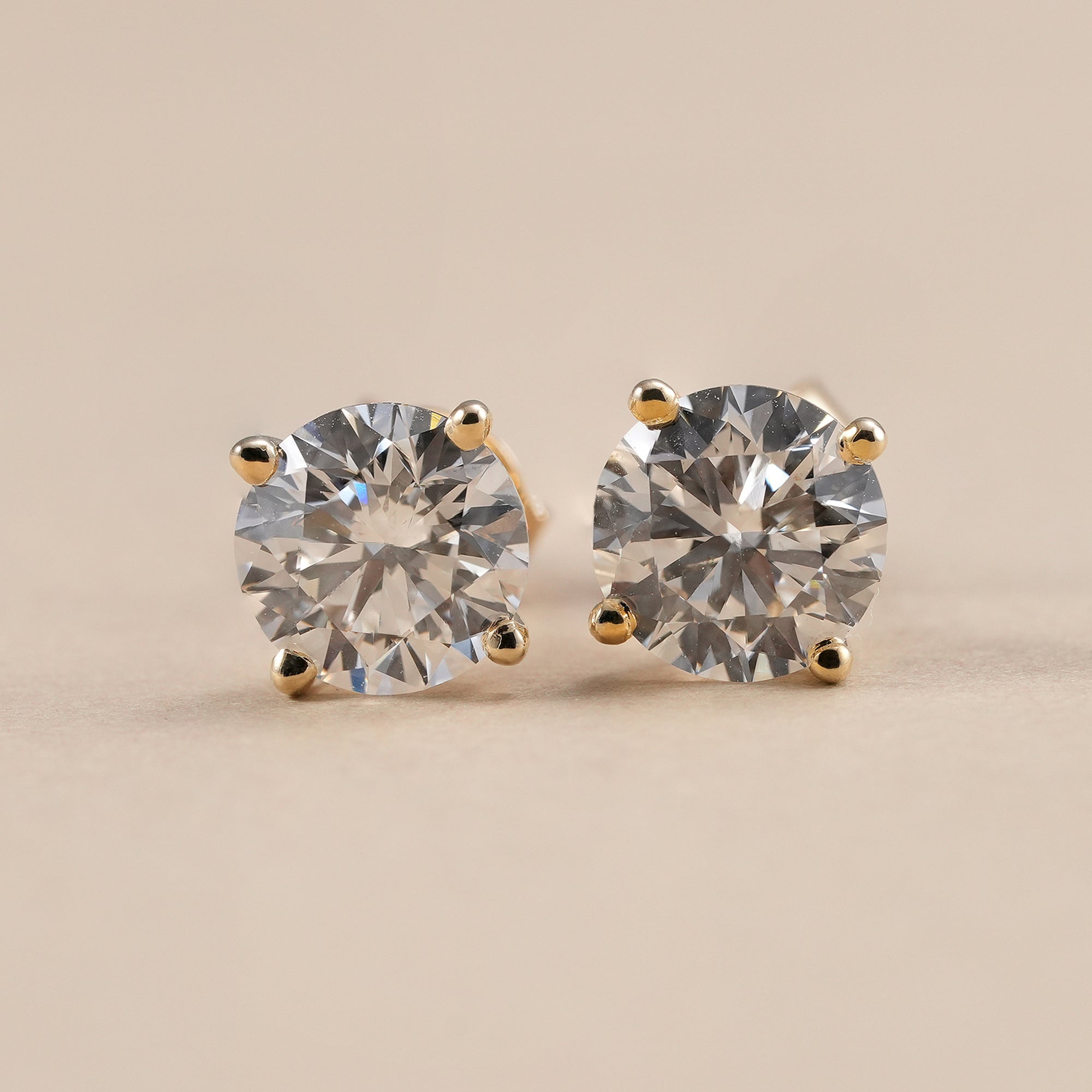 Round solitaire lab grown diamond stud earrings in classic four prong gold setting