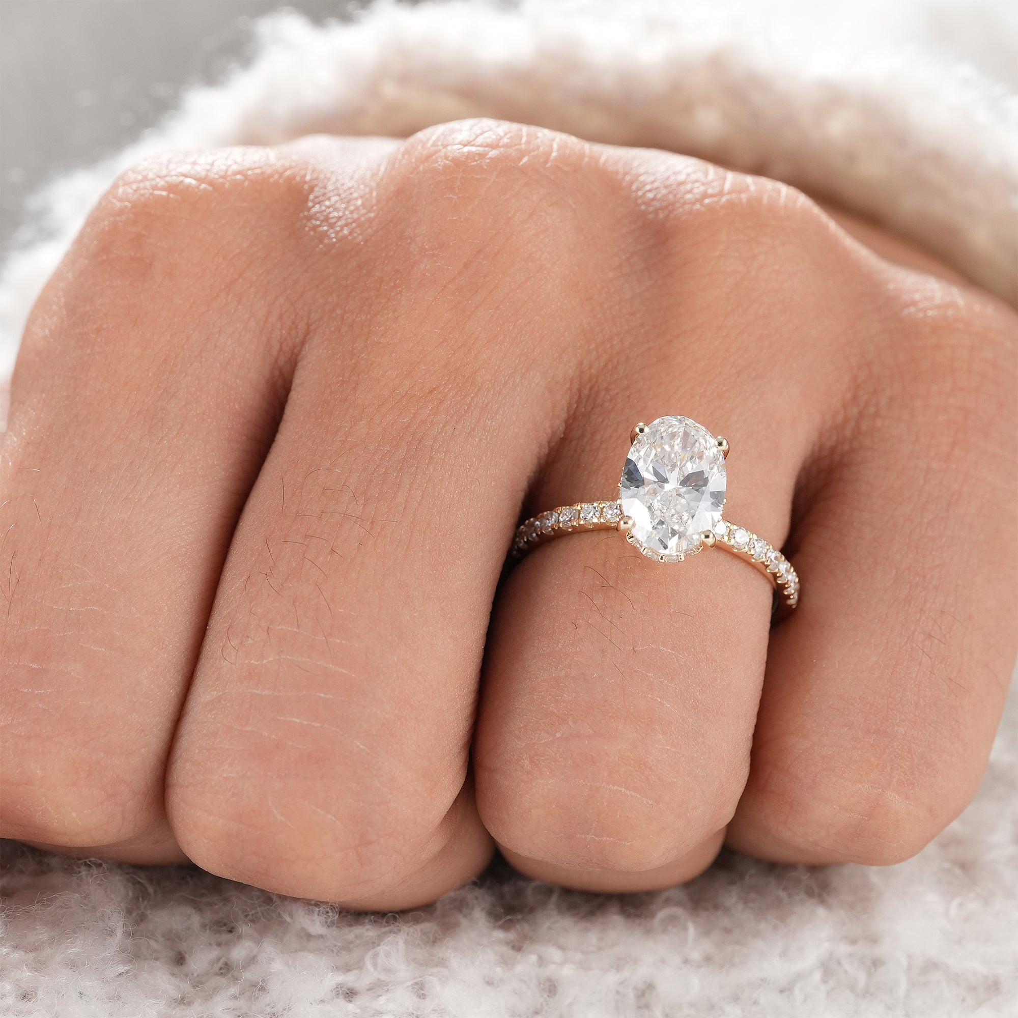 Oval diamond ring with pavé band and hidden halo design.