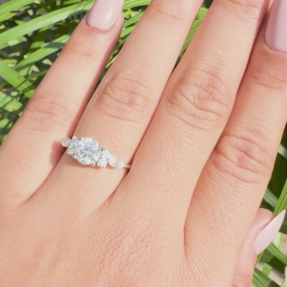 Three stone lab grown diamond engagement ring featuring round center and marquise sides.