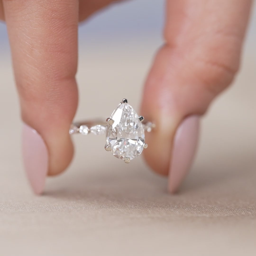 Lab grown diamond pear engagement ring with marquise and round accent stones