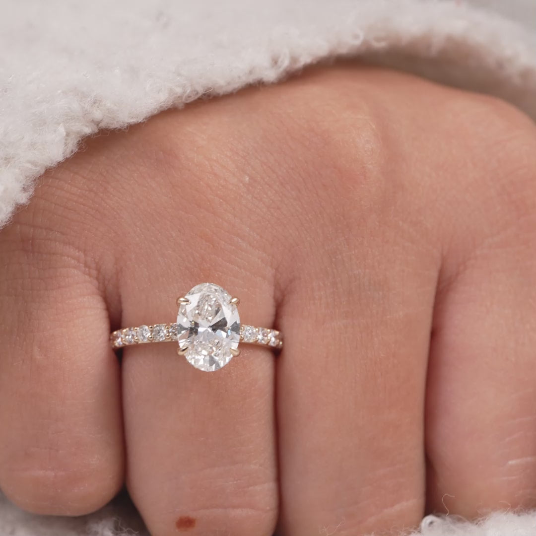 Oval cut lab diamond engagement ring with hidden halo and pavé band