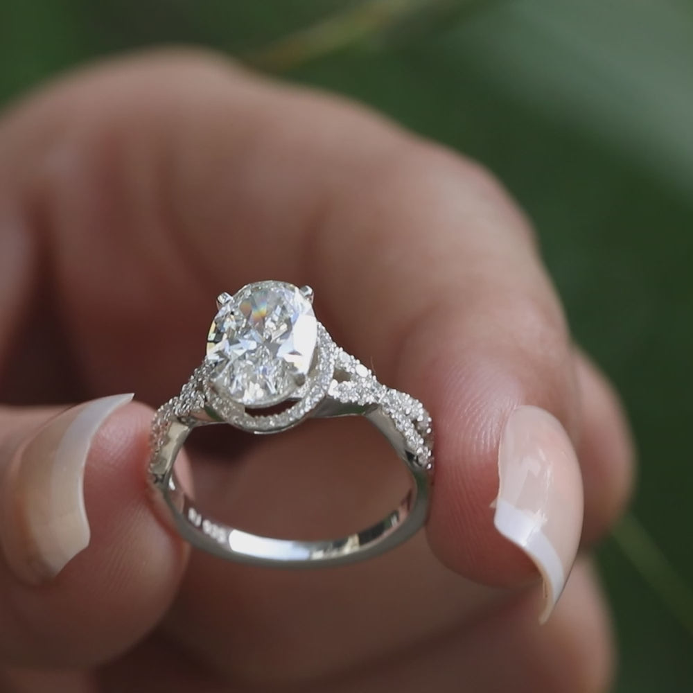 Sparkling oval diamond engagement ring featuring an intertwined diamond-studded shank.